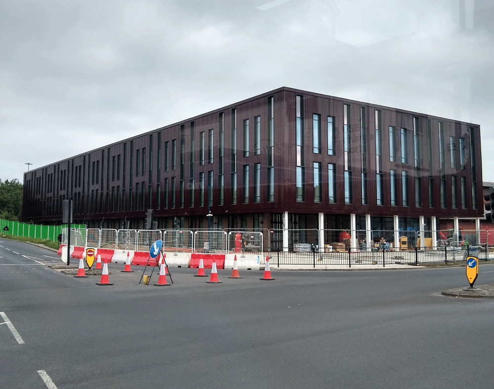 Modern building under construction with traffic cones in view