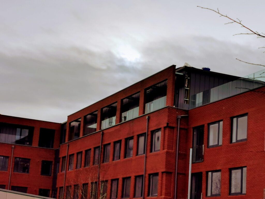 Red brick office building under cloudy sky backdrop