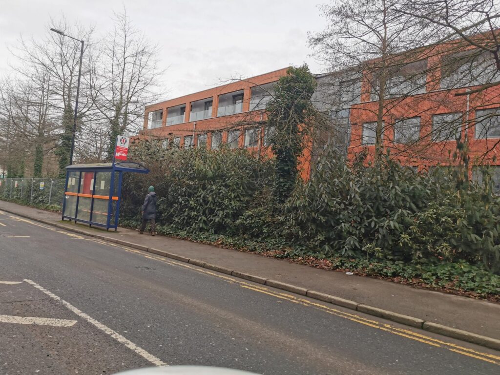 Bus stop and brick building surrounded by greenery