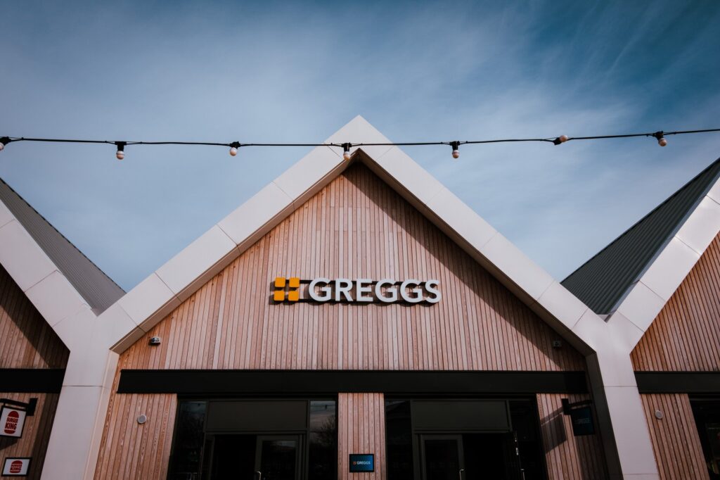 Modern bakery storefront with Greggs sign under blue sky