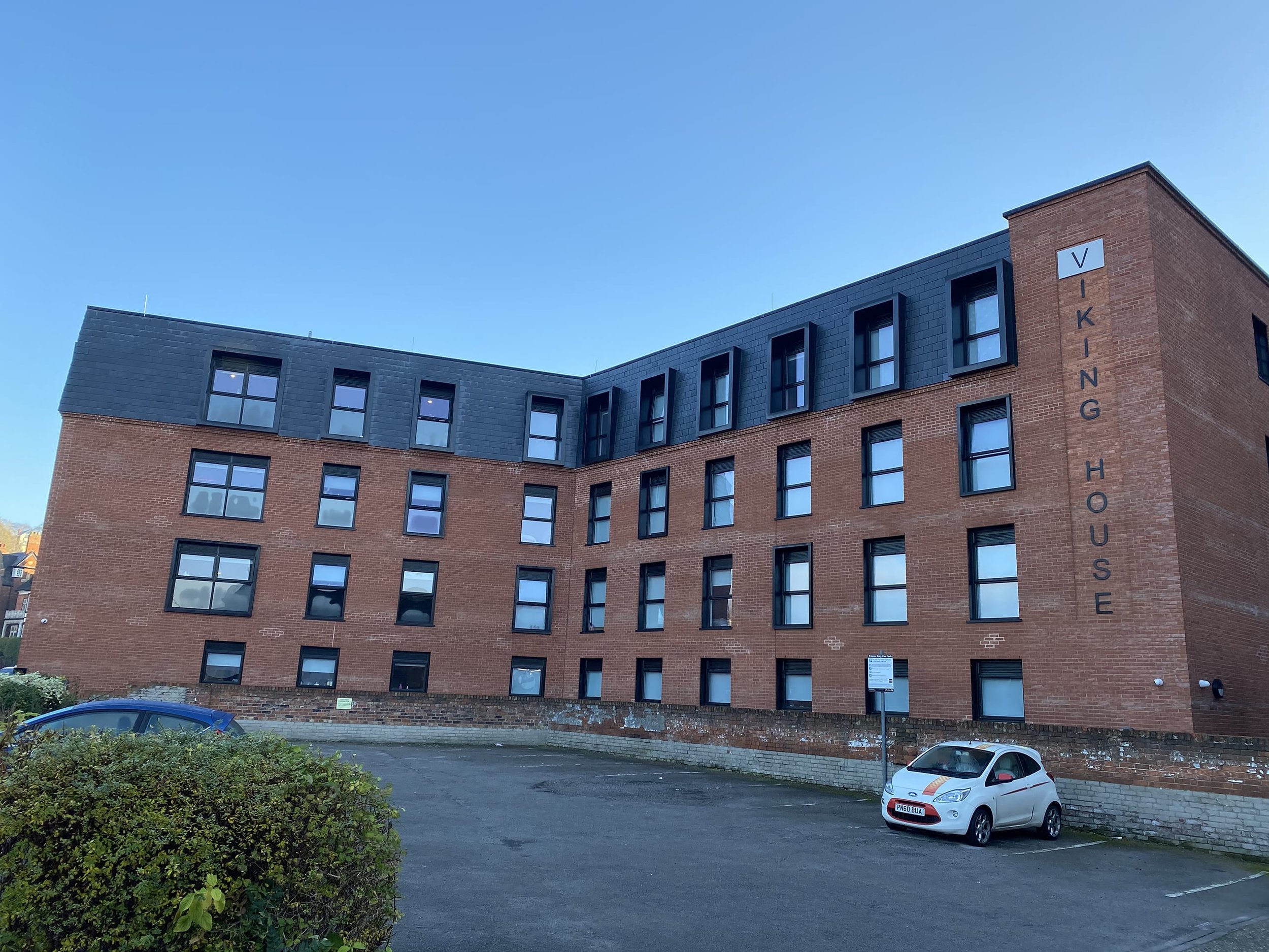 Four-story brick building with parking lot and car in front