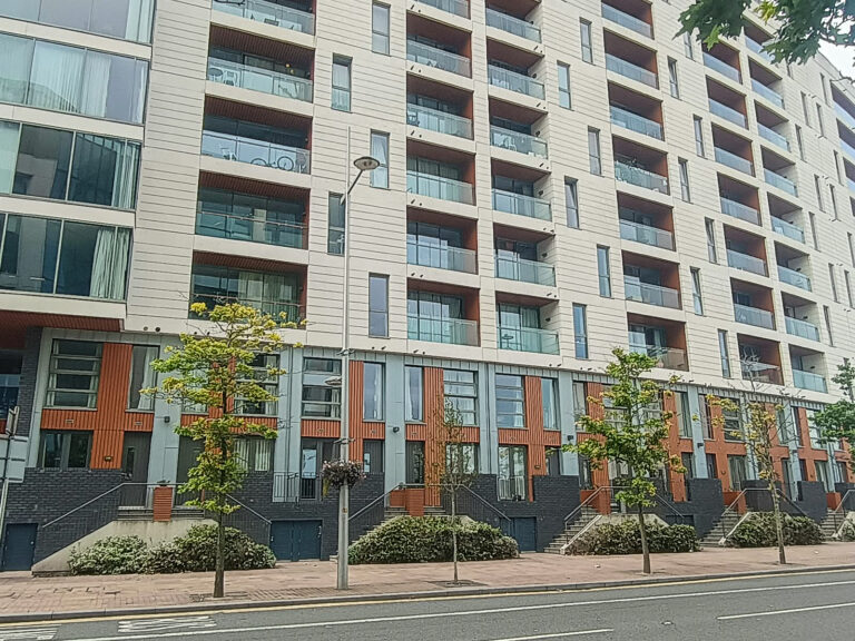 Modern urban apartment building with balconies and trees.